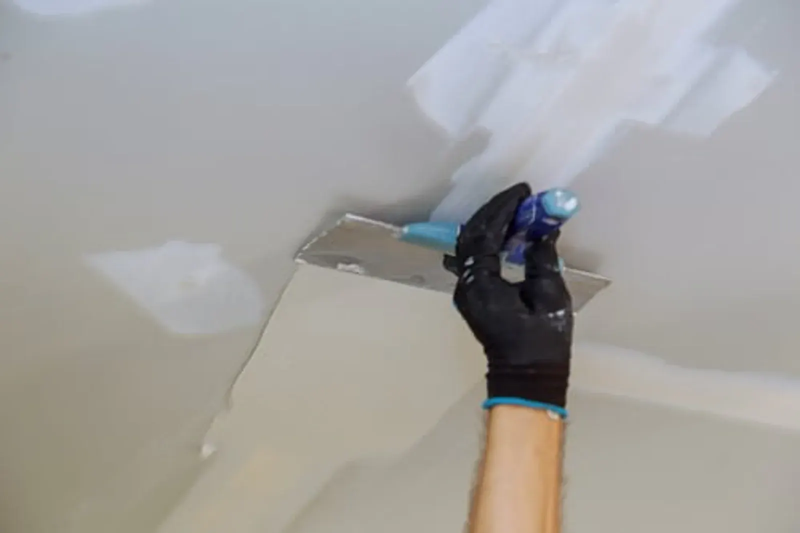 Tradesman skim-coating a drywall repair to a smooth, seamless finish